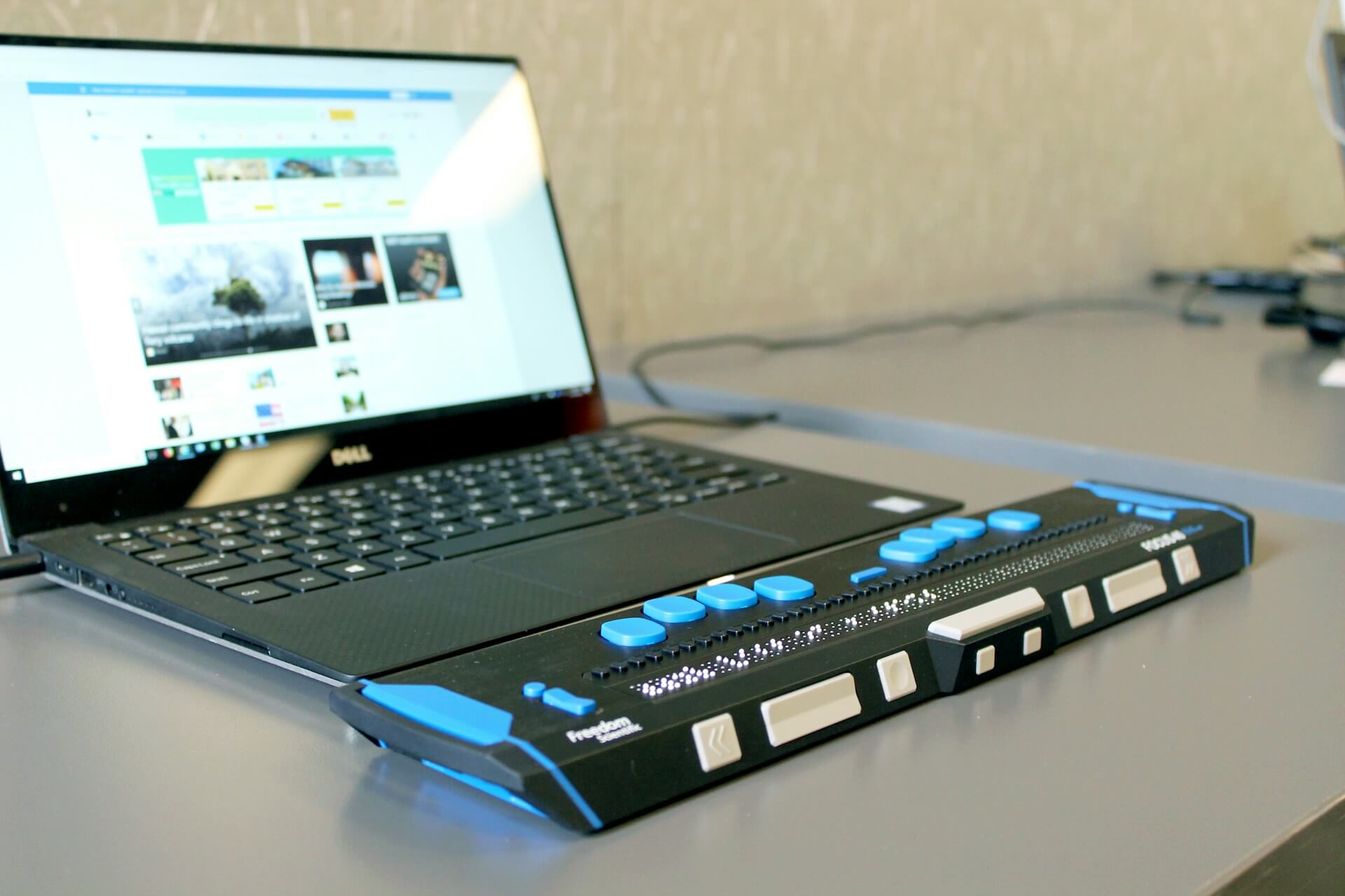 Laptop with a braille keyboard on a work table.